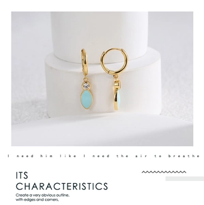 Macro shot of gold-plated leaf earrings with blue enamel and sparkling zircon accents