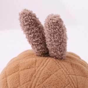 Detailed close-up of plush rabbit ears and diamond quilted texture on a baby winter hat