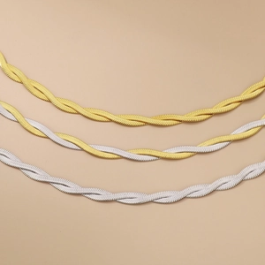 Detailed view of braided herringbone necklaces in gold, silver and bicolor steel finishes