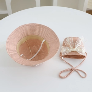 Close-up of pink straw hat and mini bag set with white lace bows for girls