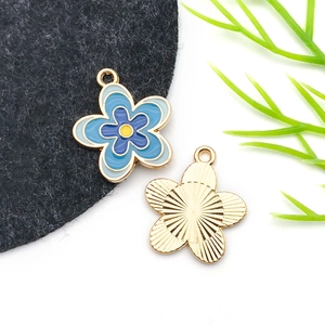 Detail of blue flower enamel pendants with golden base and radial textured back for DIY