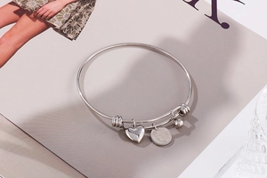 Detail of silver queen coin bracelet with heart and steel bead charms on a magazine