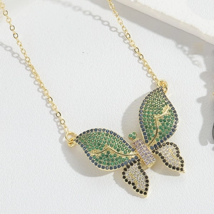 Macro shot of gold butterfly pendant with colorful zircons on a textured white surface
