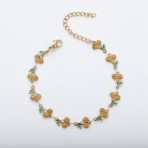 Detailed close-up of 18k gold-plated cherry bracelet with green enamel and lobster clasp