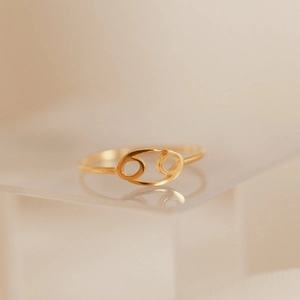 Golden stainless steel Cancer zodiac sign open ring displayed on an acrylic block