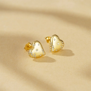 Macro shot of gold-plated heart-shaped stud earrings with sparkling cubic zirconia detail