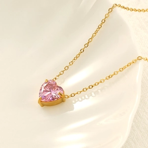 Elegant gold chain necklace with a sparkling heart-shaped pink zircon pendant on a white plate