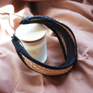 Detail of brown raffia woven headband with black fabric lining next to a scented candle