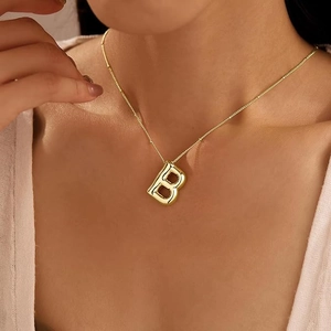 Detail of 18K gold-plated balloon letter B pendant necklace on female neck