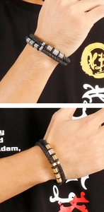 Detail of woven black leather bracelet with silver and gold metallic ring accents