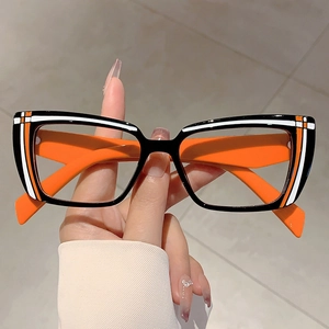 Cat-eye blue light glasses with black frames and vibrant orange temples in hand