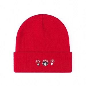 Red cuffed knitted beanie hat featuring three cute embroidered mushrooms on a white background
