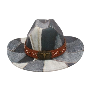 Detail of denim patchwork cowboy hat with leather band and vintage cattle skull buckle