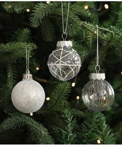 Close-up of glitter-patterned Christmas balls with mesh and stripe details on a tree