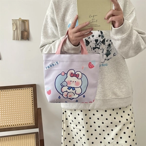 Close-up of lilac canvas tote bag with cute rabbit print held by a person in a cozy setting