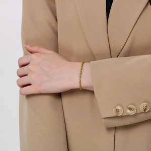 Detailed view of an 18K gold rope chain bracelet worn with a professional office suit