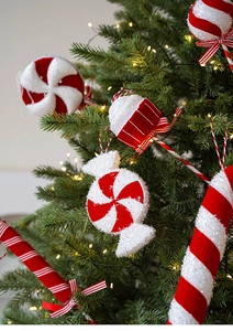 Close-up of red and white glittery candy ornaments hanging on a festive green Christmas tree