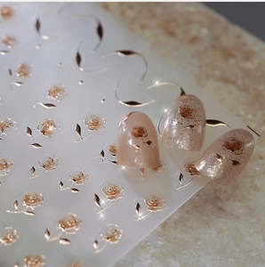 Detailed macro view of 3D gold rose nail stickers with metallic frosted lines on nails