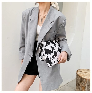 Fashionable cow print envelope clutch bag with matching wrist strap held by a model