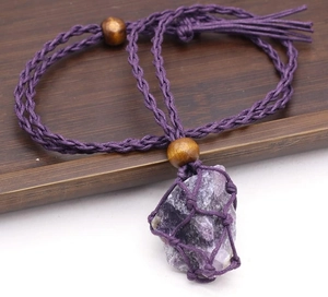 Detalle del colgante de amatista natural en una bolsa de malla tejida a mano violeta