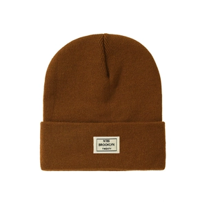 Detail of a brown knit beanie featuring a white Brooklyn N°86 woven label and ribbed texture