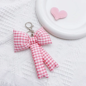 Detailed close-up of a pink checkered fabric bow keychain with metal clasp and keyring