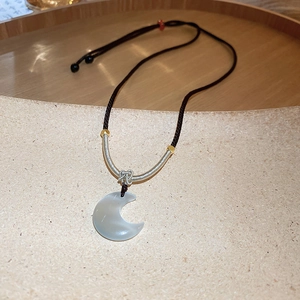 Detailed shot of moon pendant necklace with black cord and golden accents