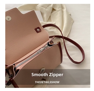 Detail view of smooth metal zipper and magnetic closure on contrast color leather bag