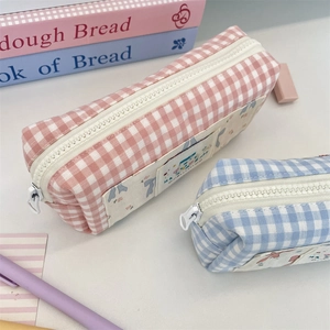 Close-up of pink and blue checkered fabric pencil cases with cute cartoon patches