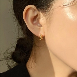 Elegant gold beaded hoop earrings for women worn on ear in a minimalist fashion style