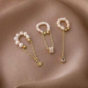 Elegant gold freshwater pearl ear cuffs with tassel charms on brown silk background