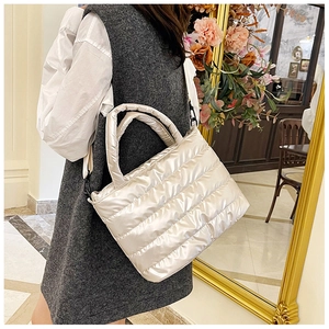 Quilted puffer tote bag in silver-white finish shown on model in a stylish indoor setting