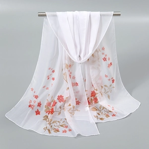 Détail d'une écharpe en mousseline avec d'élégantes fleurs rouges et feuilles dorées