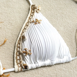 Close-up of white ribbed bikini with starfish charms, shells, and crochet trim details