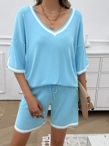 Detail view of light blue v-neck knitwear set with white stripes on hem and sleeves