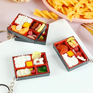 Miniature Japanese bento box keychain with realistic resin food models on white background