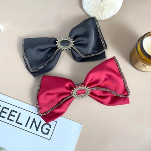 Close-up of elegant velvet red and black bow hair clips with rhinestone tassels and satin texture