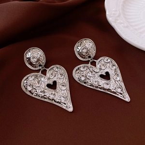 Macro shot of silver heart earrings with pavé diamonds and a vintage textured finish