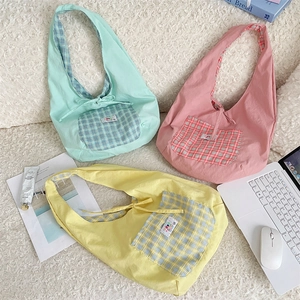 Detailed view of canvas tote bags with plaid pockets in mint green, pink, and yellow