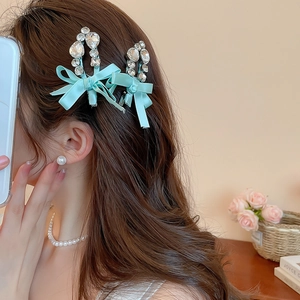Détail de barrettes nœuds en satin bleu clair avec strass sur cheveux ondulés bruns