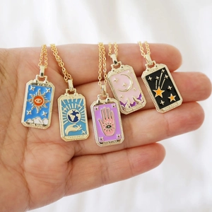 Vintage vergoldete Tarot-Halsketten mit bunten Emaille-Anhängern auf weißem Stoff
