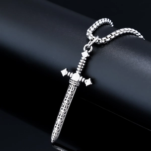Macro shot of silver sword pendant with intricate carvings and square pearl chain necklace