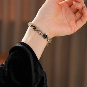 Gros plan d'un bracelet vintage doré avec pierres noires et claires sur un poignet
