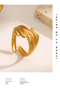 Detailed view of layered gold wavy open rings on a white surface with soft shadows
