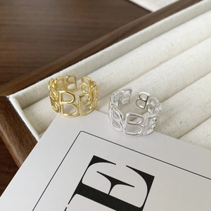 Close-up of gold and silver letter B rings on a wooden jewelry box display