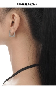 Close-up of minimalist square silver earrings worn on ear showing geometric hollow design
