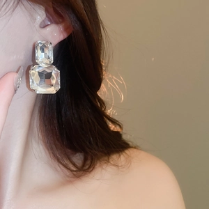 Close-up of model wearing square-cut crystal earrings with elegant stacked stone design