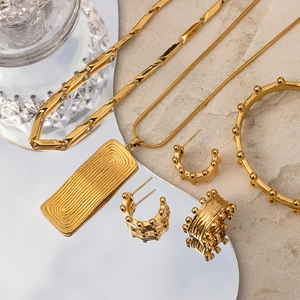 Close-up of 18K gold stainless steel jewelry set with textured edges and beaded details