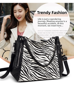 Detail of zebra print hobo bag showing silver zipper accents and textured leather straps