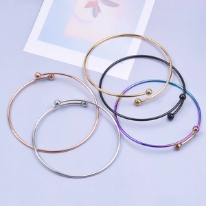 Detail view of five minimalist stainless steel bangles with metal beads in varied finishes